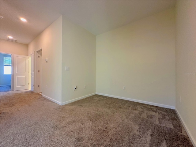 carpeted spare room featuring visible vents and baseboards