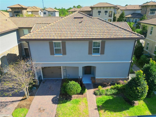 view of front of house featuring decorative driveway, a tile roof, an attached garage, and stucco siding