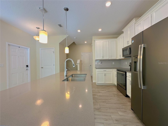 kitchen featuring visible vents, white cabinets, decorative backsplash, stainless steel appliances, and a sink