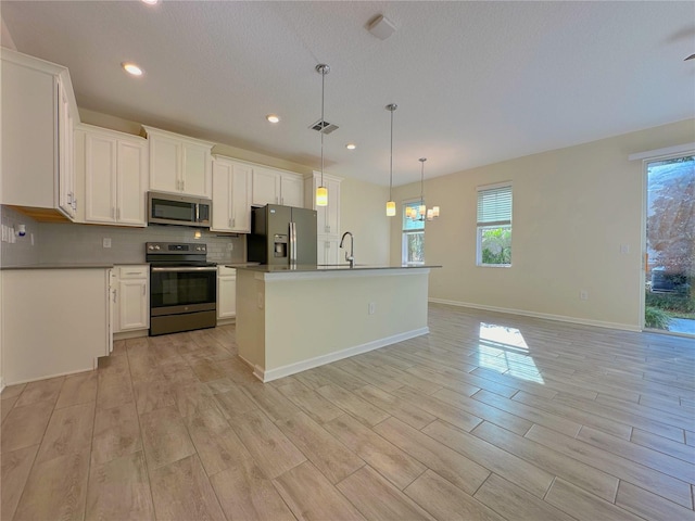 kitchen featuring light wood-style flooring, white cabinetry, visible vents, appliances with stainless steel finishes, and tasteful backsplash