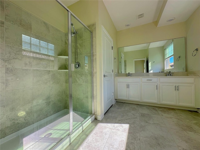 full bathroom featuring double vanity, a stall shower, a sink, and visible vents