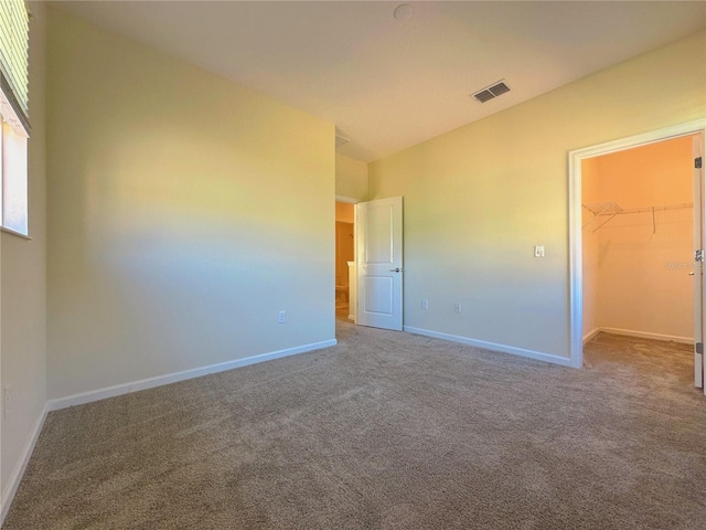 unfurnished bedroom featuring carpet flooring, visible vents, baseboards, a spacious closet, and a closet