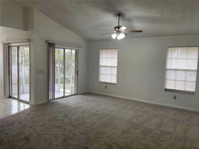 carpeted empty room featuring ceiling fan, vaulted ceiling, and a textured ceiling