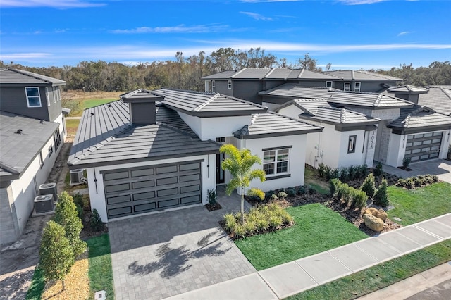 front of property with a garage, a front yard, and central air condition unit