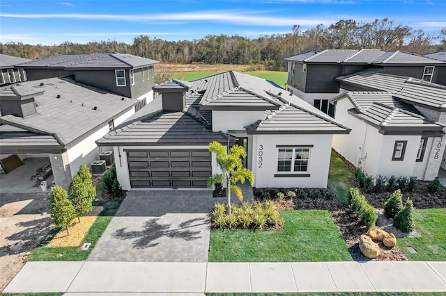 view of front property featuring a garage, central AC unit, and a front lawn