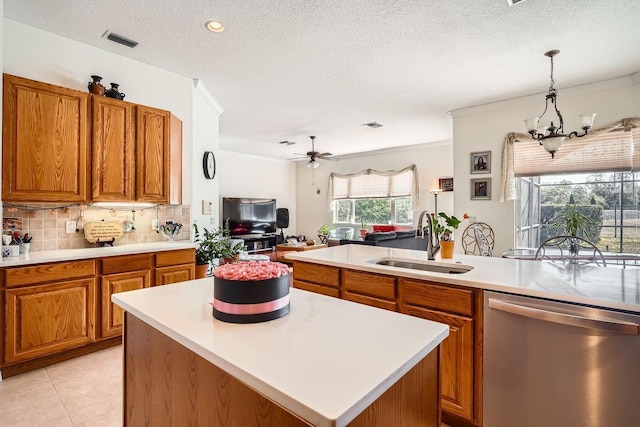 kitchen featuring sink, decorative light fixtures, a textured ceiling, dishwasher, and a kitchen island with sink