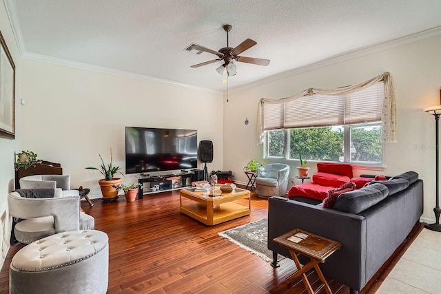 living room featuring ceiling fan, ornamental molding, wood-type flooring, and a textured ceiling