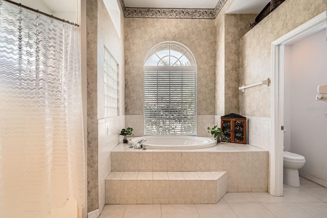 bathroom featuring tile patterned floors, toilet, and tiled tub