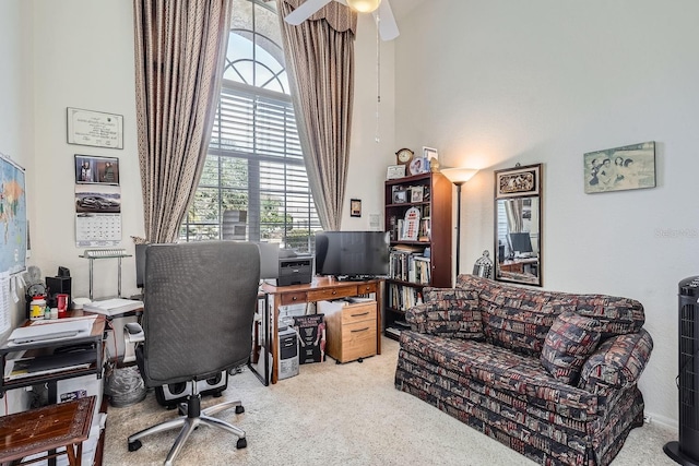 office area featuring ceiling fan, a towering ceiling, and light carpet