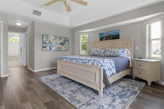 bedroom with ensuite bathroom, dark wood-type flooring, and ceiling fan