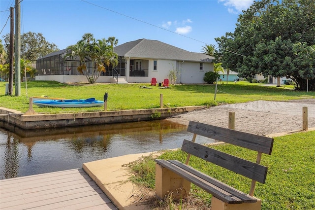 dock area with a yard, a water view, and glass enclosure