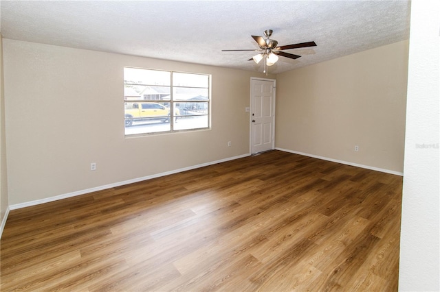 spare room with a textured ceiling, wood finished floors, a ceiling fan, and baseboards