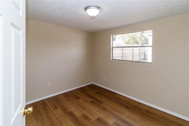 spare room with a textured ceiling, baseboards, and wood finished floors