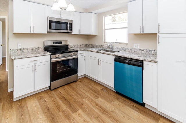 kitchen featuring appliances with stainless steel finishes, light wood-type flooring, white cabinetry, and a sink