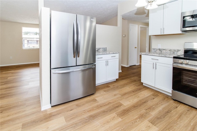 kitchen featuring stainless steel appliances, light wood finished floors, white cabinetry, and baseboards