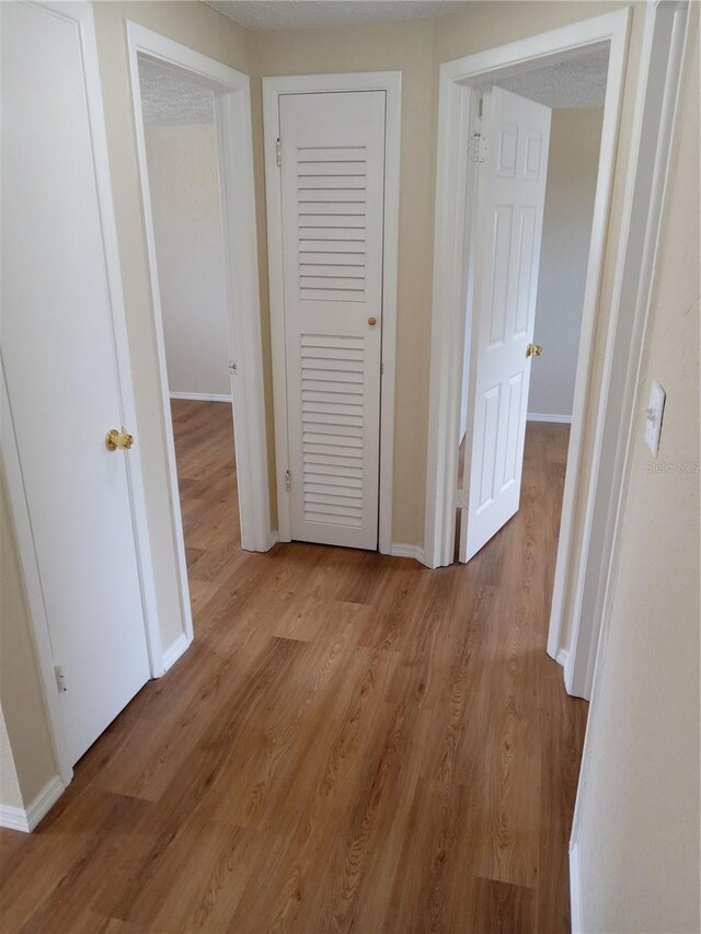 corridor with light wood-style flooring and baseboards