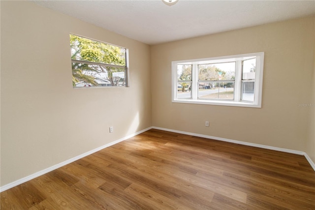 spare room featuring baseboards and wood finished floors