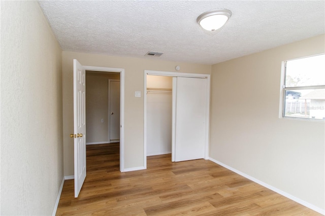 unfurnished bedroom featuring light wood finished floors, a closet, visible vents, and baseboards