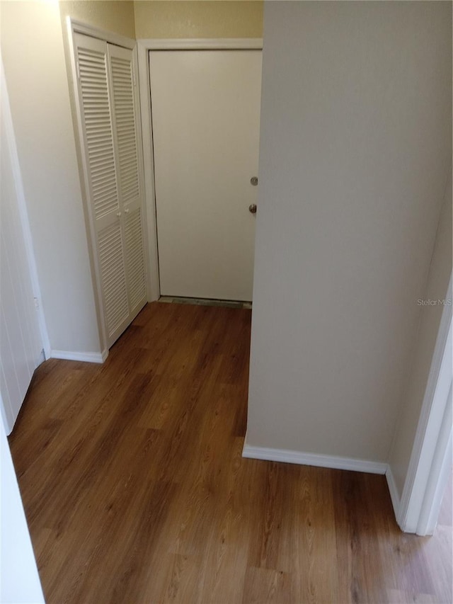 hallway featuring baseboards and wood finished floors