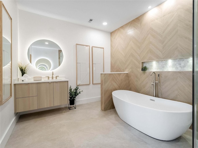 bathroom with vanity, tile walls, and a bathtub