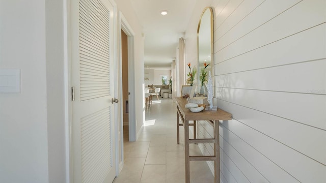 corridor with light tile patterned flooring and wooden walls