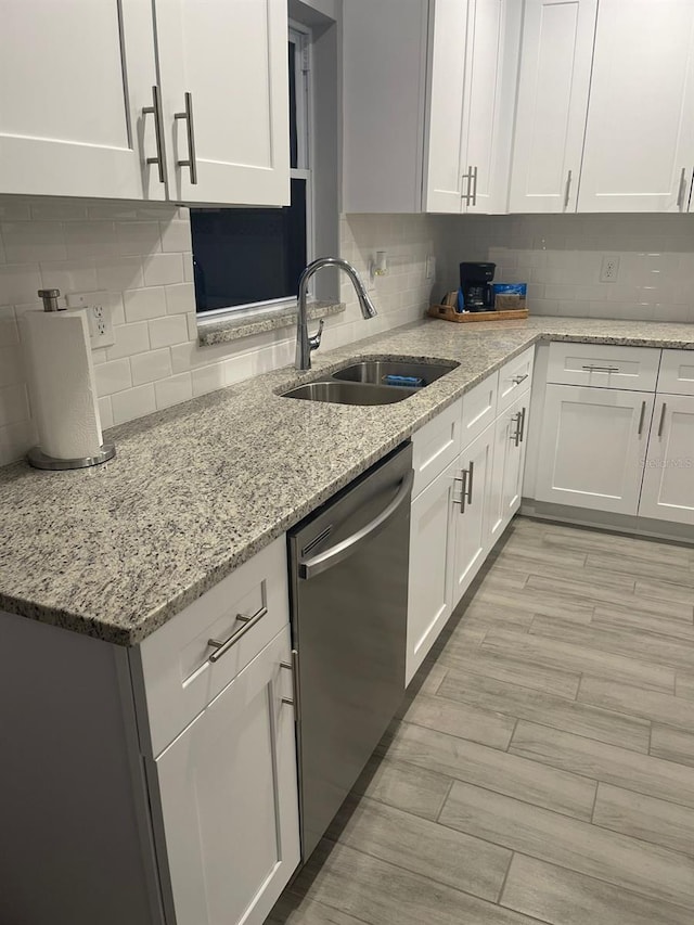 kitchen featuring white cabinetry, sink, decorative backsplash, stainless steel dishwasher, and light stone counters