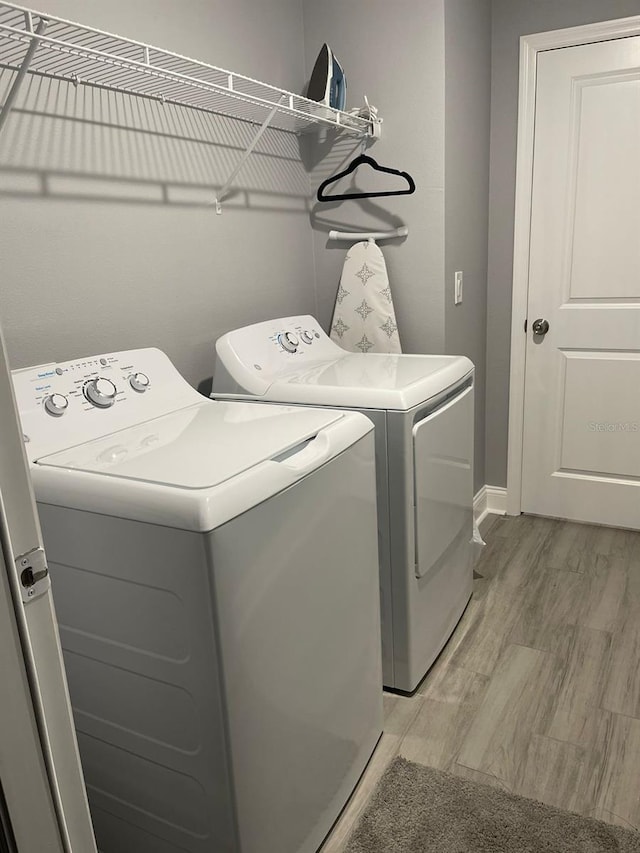 laundry area with light hardwood / wood-style flooring and washing machine and dryer