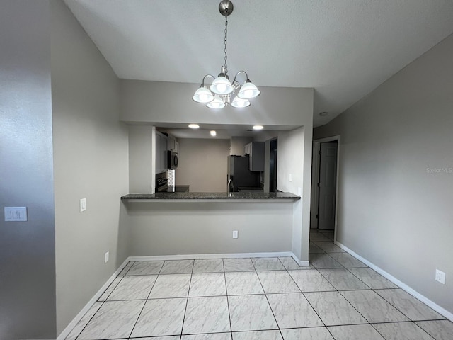 kitchen featuring dark stone countertops, appliances with stainless steel finishes, kitchen peninsula, a notable chandelier, and pendant lighting