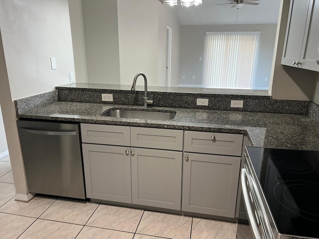 kitchen featuring sink, gray cabinets, ceiling fan, stainless steel appliances, and dark stone counters