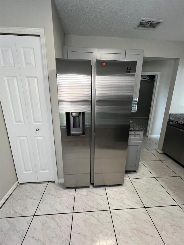 kitchen with stainless steel refrigerator with ice dispenser, gray cabinetry, a textured ceiling, and stainless steel refrigerator