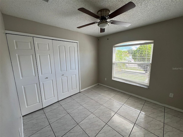 unfurnished bedroom with ceiling fan, a closet, and a textured ceiling