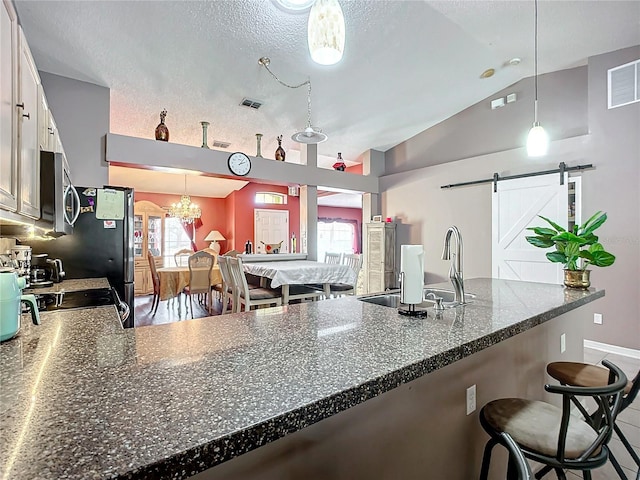 kitchen with pendant lighting, white cabinetry, a kitchen breakfast bar, kitchen peninsula, and a barn door