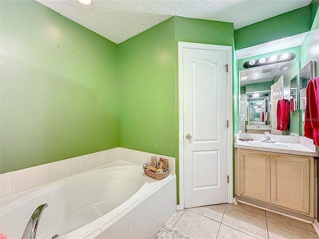 bathroom featuring vanity, tile patterned floors, tiled bath, and a textured ceiling