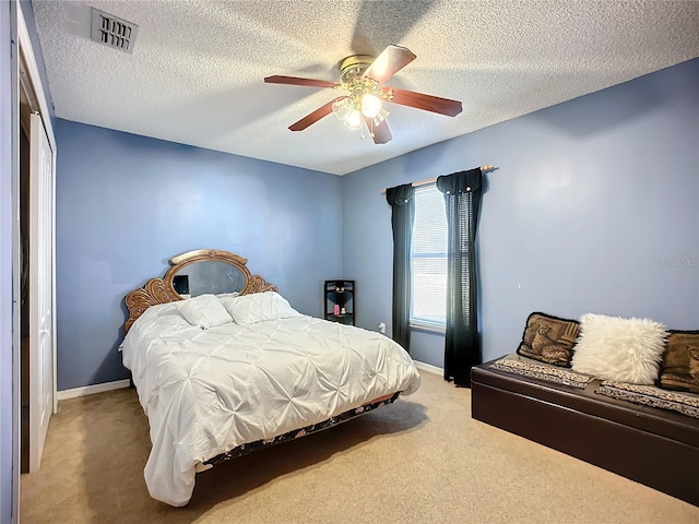 carpeted bedroom with ceiling fan and a textured ceiling