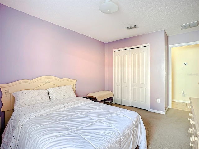 bedroom featuring light carpet, a closet, and a textured ceiling