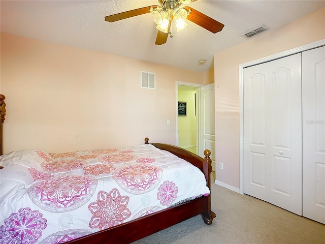 carpeted bedroom with ceiling fan, a closet, and a textured ceiling