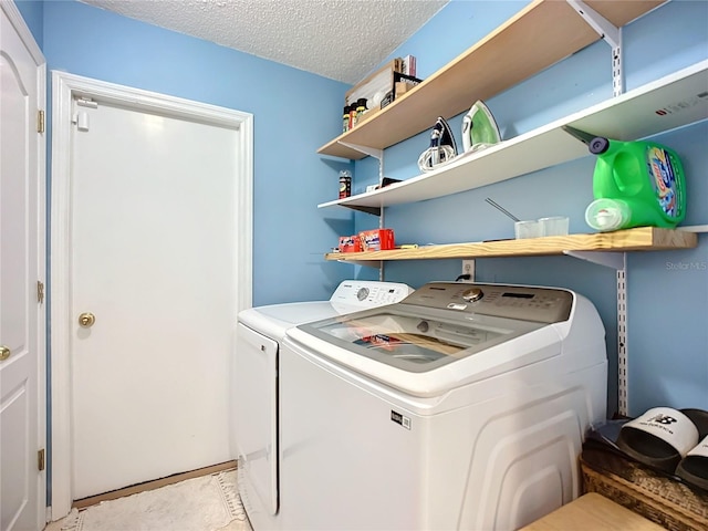 clothes washing area with washer and clothes dryer and a textured ceiling