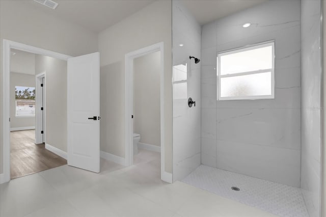 full bathroom with visible vents, tiled shower, toilet, and baseboards