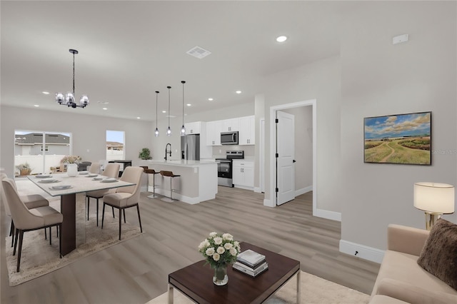 living room featuring recessed lighting, visible vents, light wood-style flooring, a chandelier, and baseboards