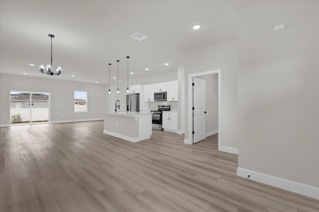 unfurnished living room featuring light wood finished floors, baseboards, visible vents, an inviting chandelier, and recessed lighting