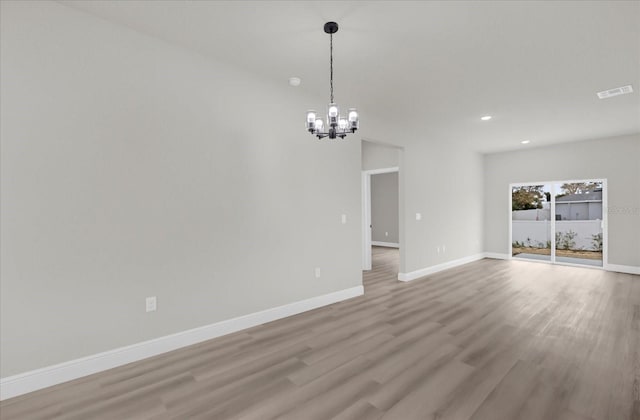 spare room featuring light wood finished floors, baseboards, visible vents, an inviting chandelier, and recessed lighting