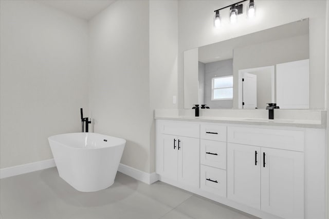 bathroom with double vanity, a freestanding tub, baseboards, and a sink