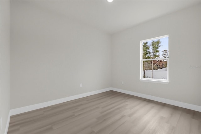 spare room with baseboards and wood finished floors