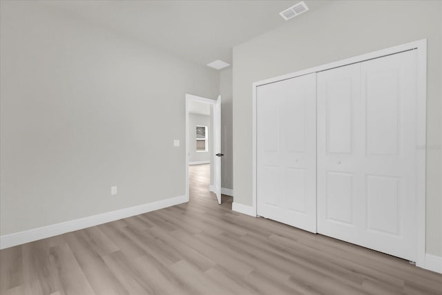 unfurnished bedroom with a closet, light wood-type flooring, visible vents, and baseboards