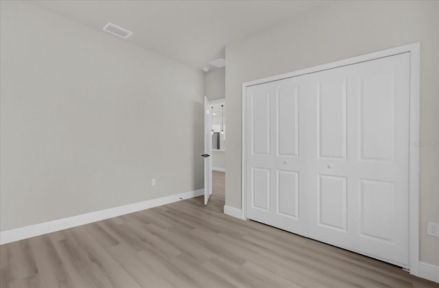 unfurnished bedroom with light wood-style flooring, visible vents, baseboards, and a closet