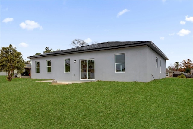 rear view of house with a lawn and stucco siding