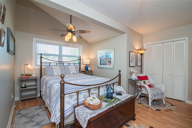 bedroom featuring wood-type flooring, lofted ceiling, ceiling fan, and a closet