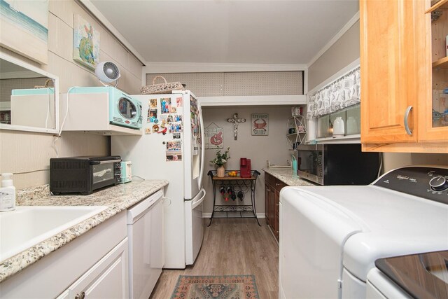 kitchen featuring white appliances, ornamental molding, washing machine and dryer, and light wood-type flooring