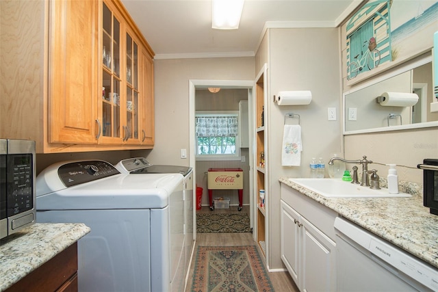 laundry room featuring ornamental molding, sink, washer and clothes dryer, and light wood-type flooring