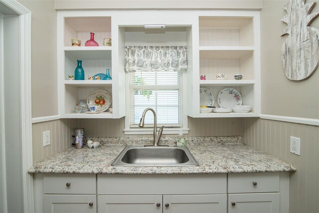 kitchen with light stone counters, sink, and built in features